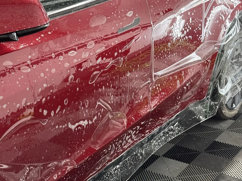 Mud-caked red car door before an exterior detail