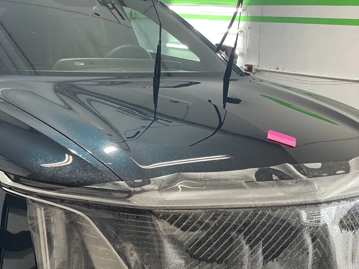 Paint protection film being installed on the front of a black SUV
